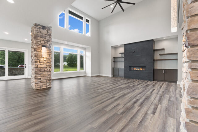 Spacious great room with vaulted ceilings, stone column detail, modern fireplace wall, and large windows in a custom home by Wannemacher Design Build in Fort Wayne, Indiana.